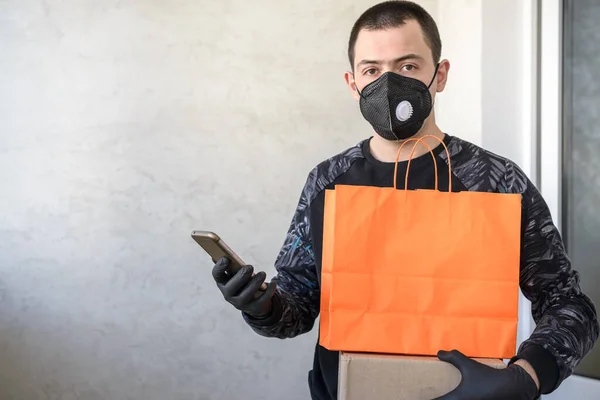 Delivery man holding paper bag with food on white background, food delivery man in protective mask and protective gloves.