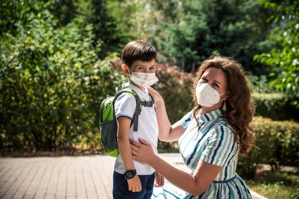 Yüzü maskeli çocuklar okula ya da anaokuluna gidiyor. Anne ve çocuk koronavirüs ve grip salgını sırasında yüz maskesi takıyor. Virüs ve hastalık koruması, kalabalık yerlerde el dezenfektanı..