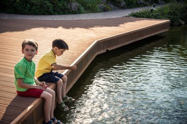 İki çocuk açık şeffaf gölde yaban ördeklerini ve küçük balık sürülerini besliyor. Erkek kardeşler en iyi arkadaşlardır. Yaz tatili arkadaşlık kavramı.