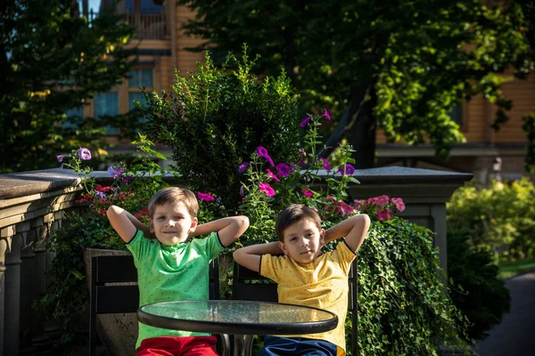 İki küçük çocuk otel restoranında ya da şehir kafesinde sağlıklı bir kahvaltı için masada bekliyor. Çocuk rahat sandalyeye oturur, rahatlar, tatilinin tadını çıkarır. Çocuk konseptiyle yaz tatili.