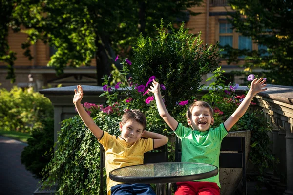 İki küçük çocuk otel restoranında ya da şehir kafesinde sağlıklı bir kahvaltı için masada bekliyor. Çocuk rahat sandalyeye oturur, rahatlar, tatilinin tadını çıkarır. Çocuk konseptiyle yaz tatili.