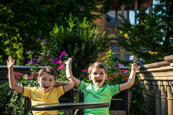 İki küçük çocuk otel restoranında ya da şehir kafesinde sağlıklı bir kahvaltı için masada bekliyor. Çocuk rahat sandalyeye oturur, rahatlar, tatilinin tadını çıkarır. Çocuk konseptiyle yaz tatili.