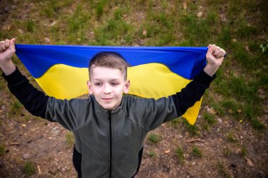 Ukraynalı çocuk elinde bayrak sallayarak Ukrayna 'daki savaşı gün batımında durdurmak için dua ediyor. Rusya 'nın Ukrayna' ya karşı savaşı. Savaşı Durdur.