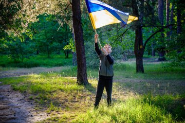 Ukraynalı çocuk elinde bayrak sallayarak Ukrayna 'daki savaşı gün batımında durdurmak için dua ediyor. Rusya 'nın Ukrayna' ya karşı savaşı. Savaşı Durdur.