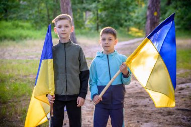 Ukrayna bayrakları iki çocuğun elinde. Çocuklar, rüzgarda dalgalanan sarı ve mavi Ukrayna bayrakları tutuyorlar. Ukrayna 'nın Bağımsızlık Günü. Bayrak Günü.