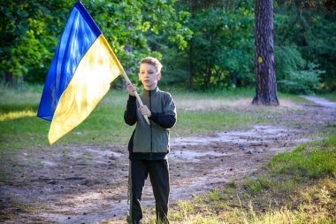 Ukraynalı çocuk elinde bayrak sallayarak Ukrayna 'daki savaşı gün batımında durdurmak için dua ediyor. Rusya 'nın Ukrayna' ya karşı savaşı. Savaşı Durdur.