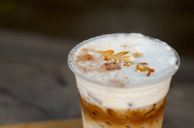 Plastik bardakta kremalı buzlu kahve bir masada, seçici odak noktası, latte sanatı