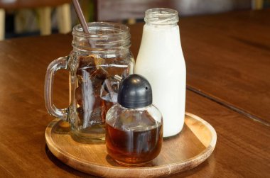 Sade buzlu kahve küpleri, süt ve şurup daire şeklinde bir ahşap tabakta.