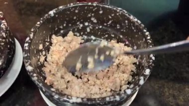 Kırmızı, siyah ve beyaz kinoa tanecikleri tahta kaşıktan yavaş çekimde kırsal kahverengi bir kaseye düşüyor. Çiğ ve sağlıklı malzemeler. Üst Manzara. Yüksek kalite 4k görüntü