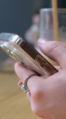 Beyaz gömlekli genç iş kadını, dijital içerikle uğraşırken şaşkınlık, güvensizlik, hayal kırıklığı ve hayal kırıklığı gibi duygular gösteren akıllı telefonuyla okuyor..