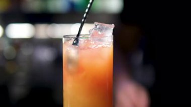 Bir bardak Aperol Spritz kokteyli. Renkli bir arka planda. Aperol Spritz 'i kokteyl kaşığıyla karıştırmak. Statik çekim. Yüksek kalite 4k görüntü