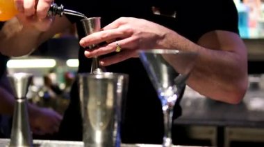 Barmen, elleri yakın plan, alkollü kokteyl hazırlıyor, ölçülmüş bardağa dökülüyor ve karıştırıcıya dökülüyor. Dikey format. Yüksek kalite 4k görüntü