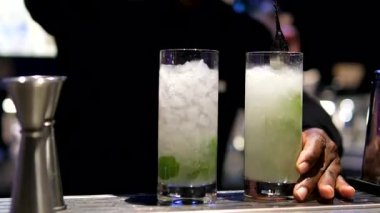 Mojito kokteyli hazırlayan profesyonel bir barmene yaklaş. Deneyimli barmen alkollü nane içeceğini karıştırır. Barmen bir bar tezgahında mojito kokteyli hazırlıyor. Yüksek kalite 4k görüntü