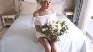 Güzel gelin yatak odasında yatağın üstüne oturan beyaz iç çamaşırı