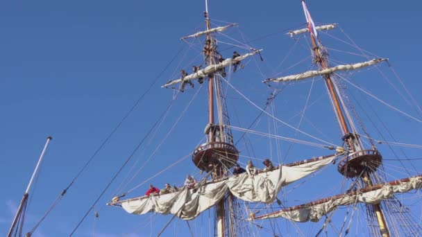 Моряки работают с парусами на высоте на традиционном паруснике — стоковое видео