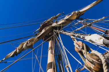 Denizciler denizde geleneksel bir yelkenli üzerinde bir yükseklikte yelken ile çalışmak