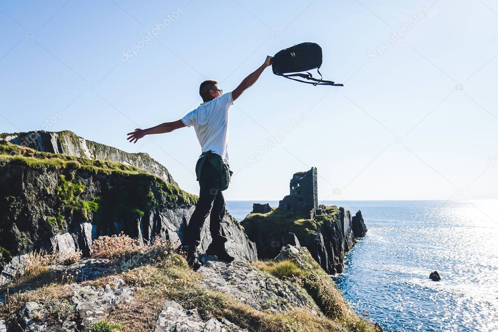 Man throws up a backpack on the background of the ruins of the fort