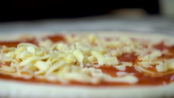 Chef pours cheese on pizza dough, slow motion — Stock Video