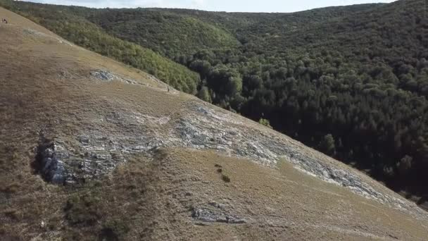 Egy férfi egy fehér inget, és a mellény basszusgitározni a hegyen. Légifelvételek — Stock videók