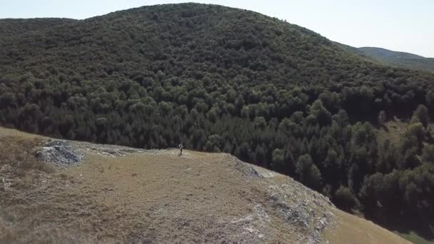 A man in a white shirt and waistcoat playing bass guitar on a mountain. Aerial view — Stock Video