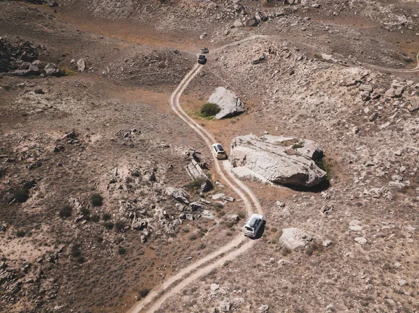 Un convoi de voitures parcourt la steppe entre poussière et pierres. Vue aérienne au Kazahstan — Photo