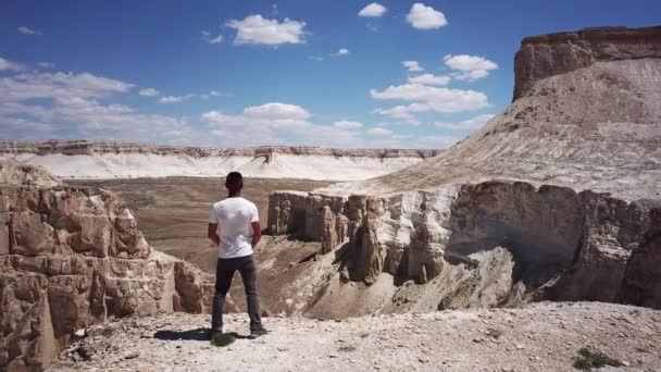 Man looks into the distance in the deserts and mountains in Kazakhstan like from another planet — Stock Video