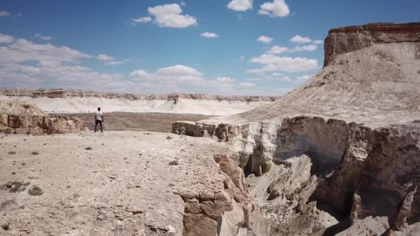 Man looks into the distance in the deserts and mountains in Kazakhstan like from another planet — Stock Video