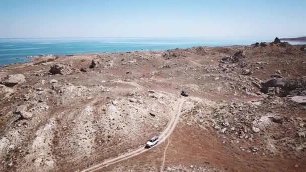 A convoy of cars rides the steppe among dust and stones. Aerial view in Kazahstan — Stock Video