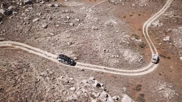 Konwój samochodów jeździ stepie wśród kurzu i kamienie. Widok z lotu ptaka Kazachstanu — Wideo stockowe