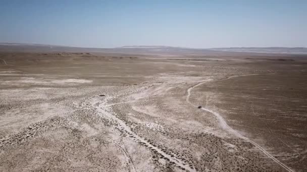 Машина пересекает пустыню, оставляя пыль. Населённые пункты Казахстана, похожие на Аризону — стоковое видео