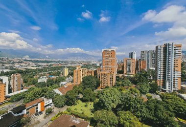 Medellin, Antioquia, Kolombiya. 14 Ocak 2021: El Poblado mahallesi ve mavi gökyüzü binalarıyla manzara.