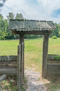 Orta Avrupa 'da iyi korunan bir parktaki yaşlı, taş kiremitli ahşap kapı, aydınlık güneşli bir günde çimen, ağaç ve çalıların bulunduğu antik bir Ortodoks kilisesine götürüyor.