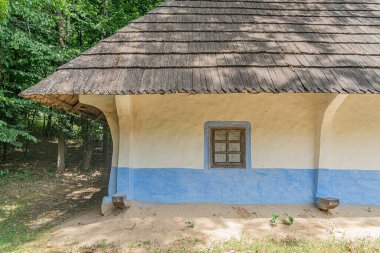 Antik Orta Avrupa köy yapısı, sazdan çatı, mavi ve beyaz çizgiler, beton ya da sıva duvarlar, açık renk, paraşüt, doğal yeşillik, gündüz ışığı, insan yok.,