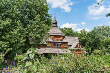 Orta Avrupa 'nın bir köyünde bulunan ve yemyeşil ve çiçeklerle bezenmiş olan antik ahşap Ortodoks Kilisesi' nin çok katlı, gri kiremitli çatısı, gabları ve bir fincanı vardır.