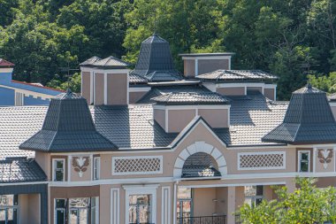 Karmaşık tasarımı, kubbeleri ve dekoratif unsurları olan tamamlanmamış bir Avrupa binasının çatı ve pencerelerinde krem rengi, bej rengi ve koyu aksanları var.