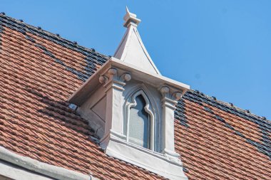 Eski bir Gotik tarzı Katolik kilisesinin köşesine yakın çekim, doğal güneş ışığı altındaki girişte karmaşık oymalar var. Dünya tonu paleti, beyaz gable ile d karşı karşıya.