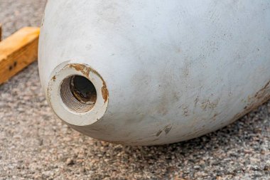 Beton bir yüzeyde üst deliği olan metal küresel bir nesnenin yukarıdan görünüşü muhtemelen bir inşaat alanında ya da avluda yansıtıcı ve desenli görünüyor.