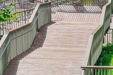 Çağdaş şehir ortamında kavisli bir tasarımı olan tahta köprü, açık renkli ahşap levhalar ve metal parmaklıklardan yapılmıştır. Köprü aşağıdan tasvir edilmiştir, derinlik duygusu göstermektedir.