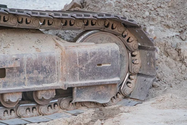 Çamurlu arazide tekerlek kazıcısı, büyük lastikler kısmen batmış, odak alanı dışında daha fazla çamur.
