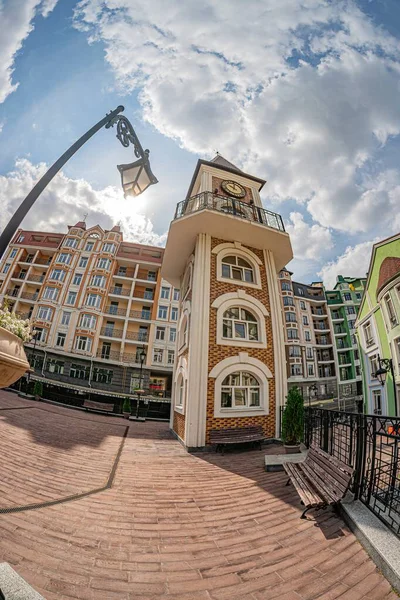 Eski Avrupa şehir sokağı, saat kulesi olan çok katlı bina, karmaşık mimari, ayrıntılı tasarımlar, birden fazla pencere, balkon, eğimli çatı, tuğlalı sokak, lamba direği, yumuşak ışıklandırma, eart