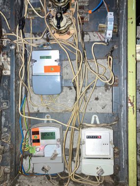 Sanayi grisi, siyahi, beyaz, kırmızı, turuncu, doğal ışıklandırma ile çeşitli sayaçları, düğmeleri ve kabloları olan karmaşık, çok katmanlı bir elektrik paneline yakın çekim.