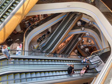 Modern mağaza iç mimarisi, TSUM Kiev Sleek cam paneller, eğri yüzeyler, çoklu yürüyen merdivenler, metalik parıltı, ahşap kaplama, doğal lig Kyiv, Ukrayna 08-03-2025