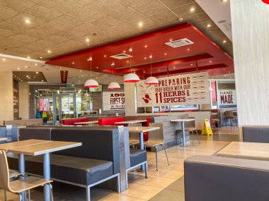 KFC Kiev 'in içi - Kırmızı, beyaz, siyah restoran alanı, teneffüs lambaları, masalar, sandalyeler, markalaştırma tabelaları Hazırlanmış, Herbs Baharatları Yapılmış, hizmet sayısının belirtileri Kyiv, Ukrayna 07-03-2025