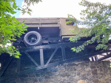 Siyah metal köprü şehir planına karşı klasik askeri araçla ön planda, doğal gündüz aydınlatma Kyiv, Ukrayna 07-13-2025