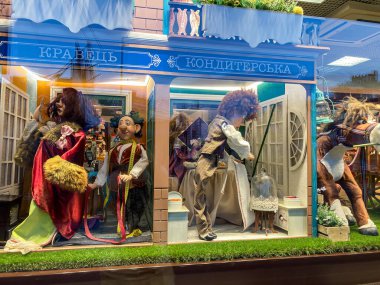 Mağaza vitrinindeki ortaçağ bebeklerinden oluşan titizlikle düzenlenmiş bir diyorama ya da daha az iddialı adam Kyiv, Ukrayna 07-26-2025 tarafından çevrelenmiş canlı kırmızı bornozlar giymiş merkez figürü.