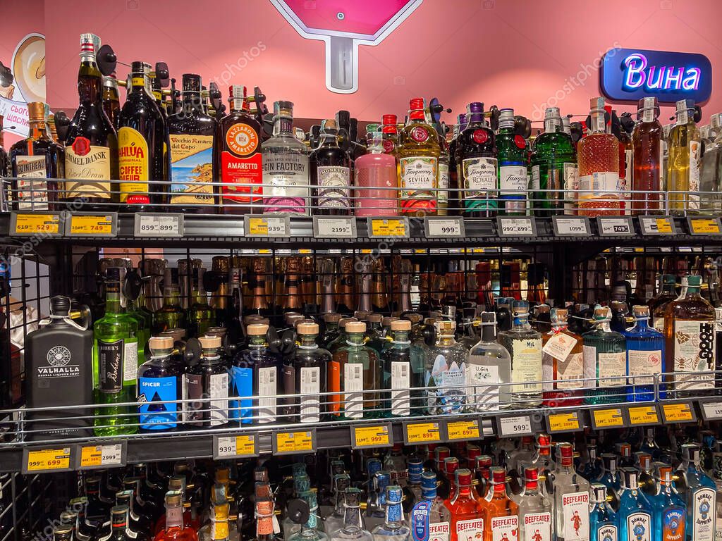 Bar shelf display case filled with various liquor bottles vodka, whiskey, rum, gin, tequila in metal racks, brightly lit, arranged densely, amber to dark hues, wel Kyiv, Ukraine 06-30-2025
