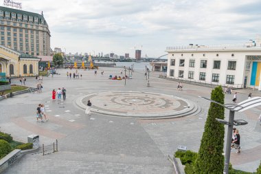 Kyiv, Ukrayna 'daki rıhtım manzarası dairesel çeşme, kırmızı tuğla kaldırım, mavi ve beyaz binalar, canlı renkler, hareketli kalabalık Kyiv, Ukrayna 07-06-2025