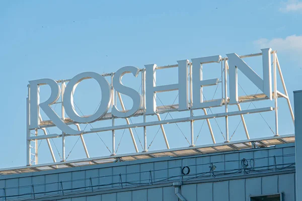 Roshens fabrikasının yakın çekim görüntüsü, bir gece veya alacakaranlık gökyüzü ile aydınlatma işareti dağınık bulutlar Paneller veya fayans gibi ön cephe ayrıntıları Kyiv, Ukrayna 07-03-2025
