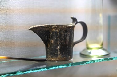 Antika kapları olan antika eczane dolabı, çatlak ve rengi değişmiş geniş yuvarlak tencere düzensiz şekil ve dizayn edilmiş boyun çevresi daha küçük tutacağı olan sıvı camlar veya yansıtıcı bardaklar.