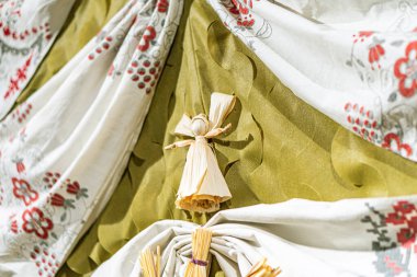 Minyatür peri masalı sahnesi. İçinde saman ve çiçek elementleriyle çevrili saman saçlı tahta bir oyuncak bebek var. Koyu yeşil arkaplan, açık yeşil arkaplanla tezat oluşturuyor.